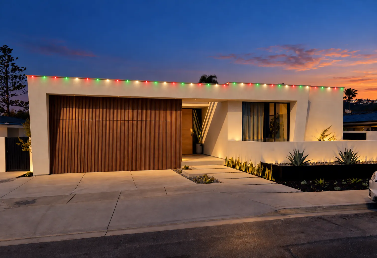 Modern single-story home with multicolor holiday lighting along the roofline at dusk