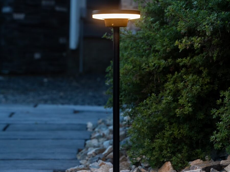 Warm path light beside a paved courtyard and garden planting